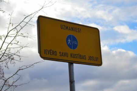 Tāpat gar promenādi uzstādītas šādas ceļa zīmes, kas atgādina, ka šaurais ceļš ir sadalīts divās daļās - viena gājējiem, otra velosipēdistiem.