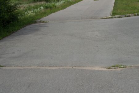 Kārtējā iebrauktuve, kur kopīgais gājēju un velosipēdu ceļš pārtrūkst. Šeit tā ir sevišķi nejēdzīga, jo ved uz zaļu pļavu.