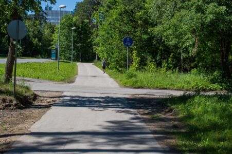 Krustojumā ar citu ceļu kopīgais gājēju un velosipēdu ceļš ir bez apmalēm, kas būtiski uzlabo braukšanas komfortu.