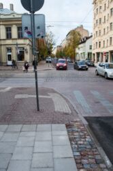 Šajā kadrā redzams jaunais (apakšā) un iepriekšējā gada (augšā) taktilā bruģa ieklāšanas veids. Iepriekš raupjais bruģis ieklāts ietves vidū, savukārt šogad ieklāts ietves malās.