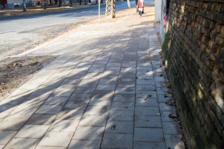 Savukārt citviet raupjais bruģis nav ieklāts ne gar fasādes zonu, ne gar zālāja zonu.