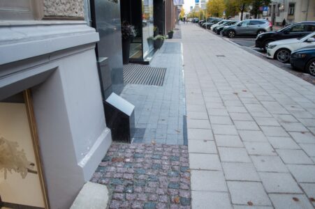 Dažviet gar fasādēm atstāts iepriekšējais gludais granīta bruģis.